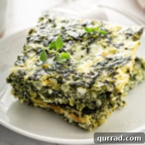 Two squares of baked spinach and feta cheese casserole stacked, a perfect serving size.