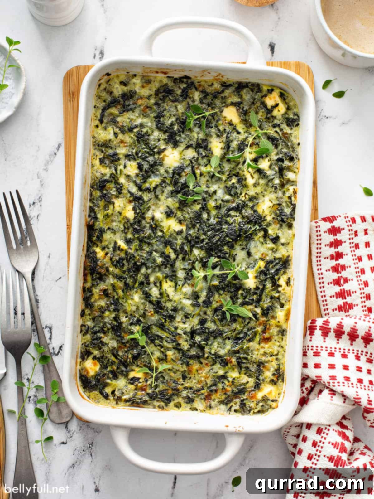 Mediterranean Feta Spinach Bake 6 A baked spinach casserole in a pristine white baking dish, showing its appealing texture and golden edges.