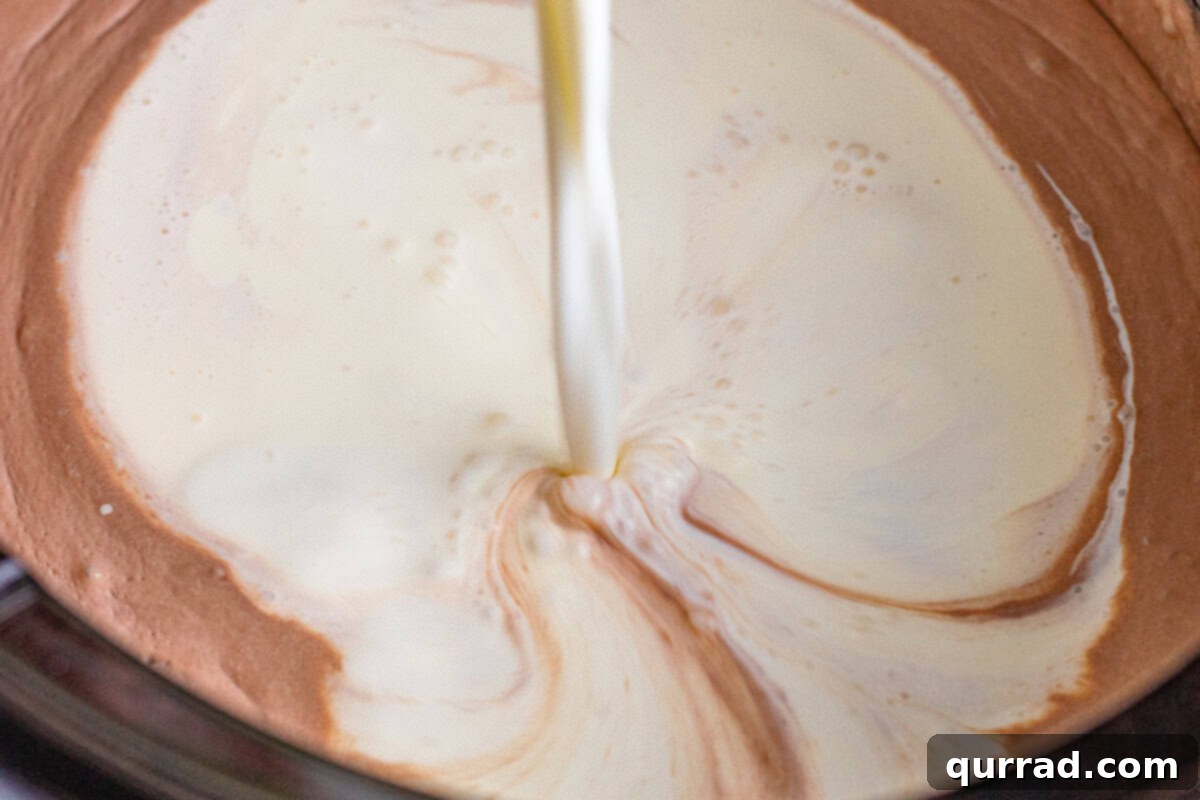 Dreamy Slow Cooker Hot Cocoa 6 milk and cream being added to chocolate in crockpot