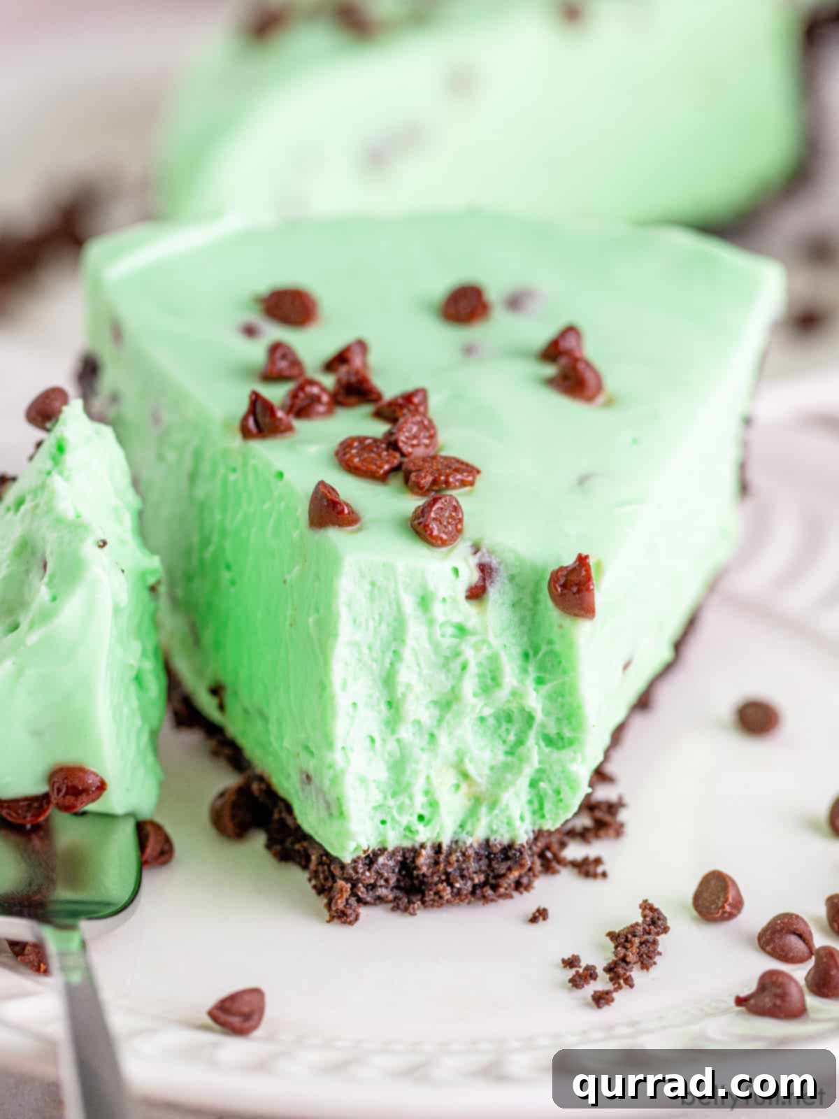 Effortless Mint Chocolate Chip Cheesecake 2 A close-up view of a perfectly sliced Mint Chocolate Chip No Bake Cheesecake, showcasing its smooth green filling and rich Oreo crust.