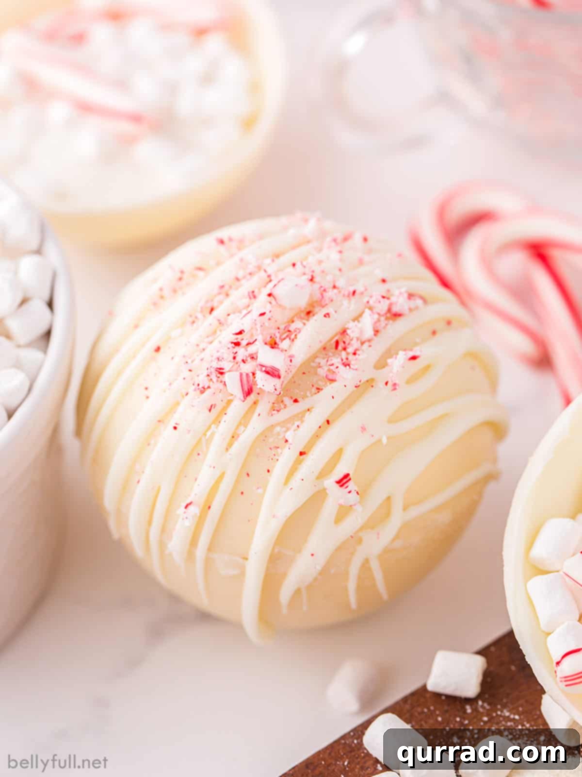 White Hot Cocoa Magic Melts 2 A beautifully crafted peppermint white hot chocolate bomb ready to be enjoyed, showcasing its elegant white shell and festive peppermint garnish.