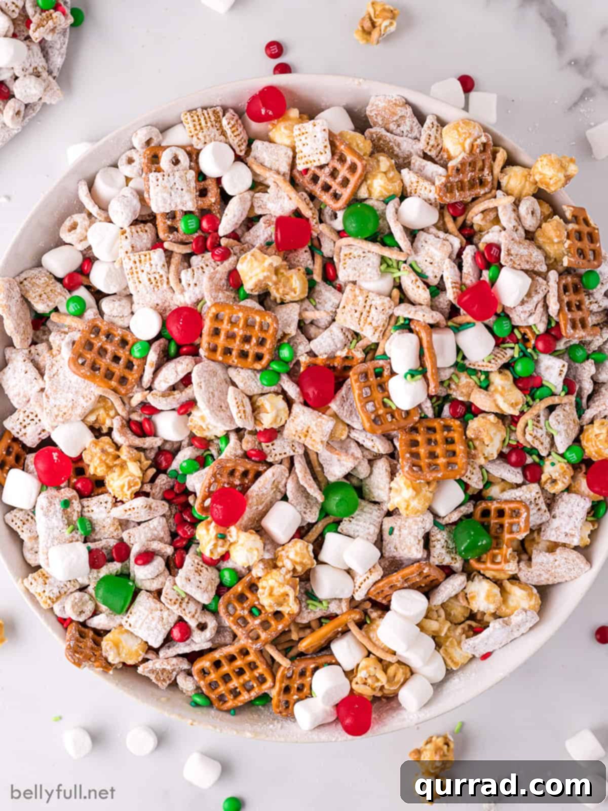 Reindeer Chow 2 Overhead view of a large bowl of festive Christmas Chex Mix, featuring a delightful blend of cereals, pretzels, chocolates, and marshmallows, ready for holiday snacking.