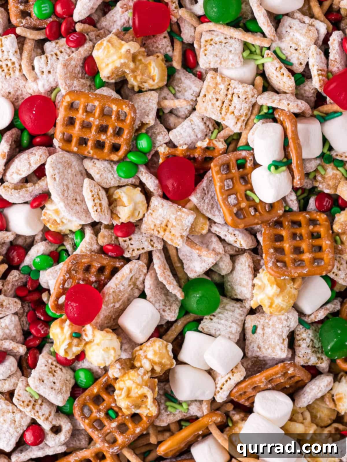 Reindeer Chow 3 Close-up detailed view of homemade holiday Chex Mix, showcasing a rich variety of cereal pieces, crunchy pretzels, colorful M&Ms, soft mini marshmallows, and other delightful sweet and savory components.
