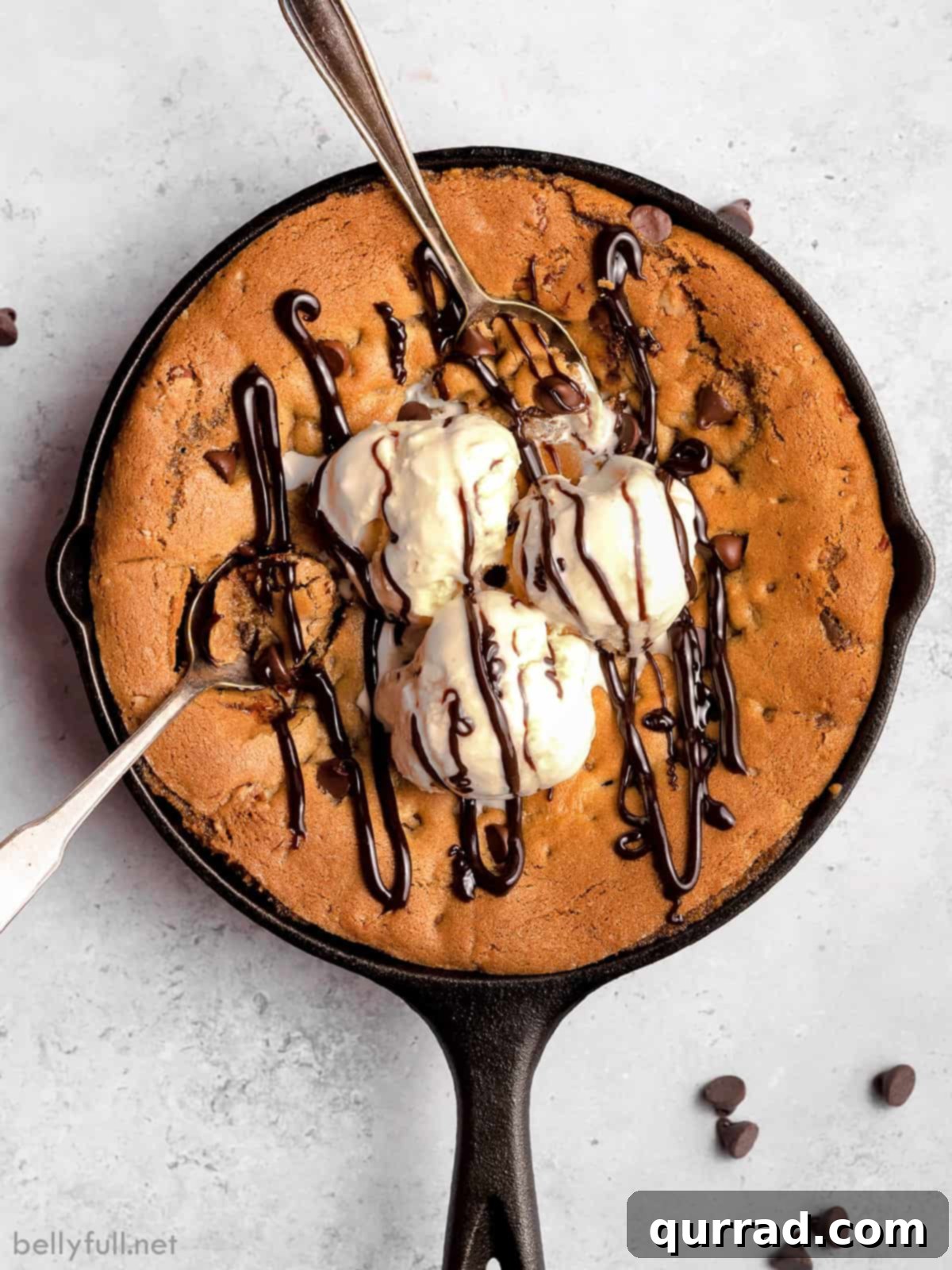 A skillet chocolate chip skillet cookie with three scoops of ice cream and syrup melting beautifully