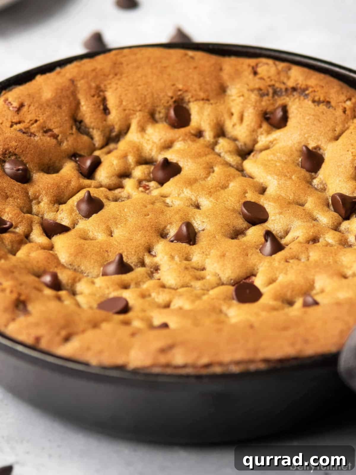 Close-up of a skillet cookie with an abundance of melted chocolate chips on a rustic wooden surface
