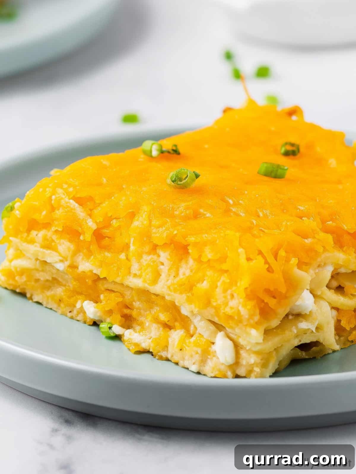 A square slice of pierogi lasagna on a blue plate, showcasing its golden-brown top and distinct layers of pasta, mashed potatoes, and cheese.
