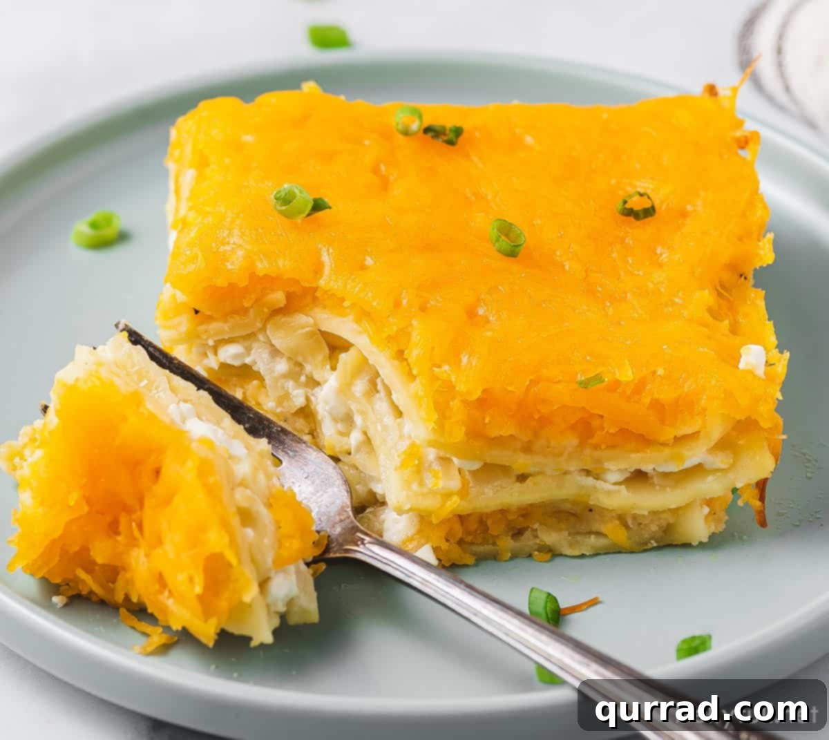 A delectable slice of pierogi lasagna resting on a white plate with a fork, ready to be enjoyed.