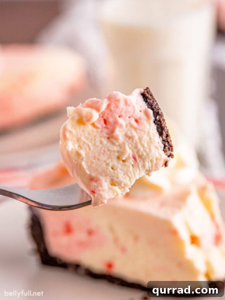 Close-up of a bite of peppermint cheesecake on a fork, showing the smooth texture and layered colors.