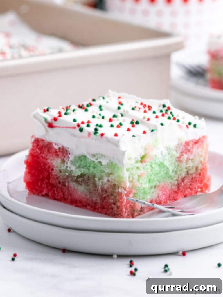Jiggly Holiday Poke Cake 2 A square slice of Christmas Jello Poke Cake on a plate, showcasing its vibrant red and green layers and creamy topping.
