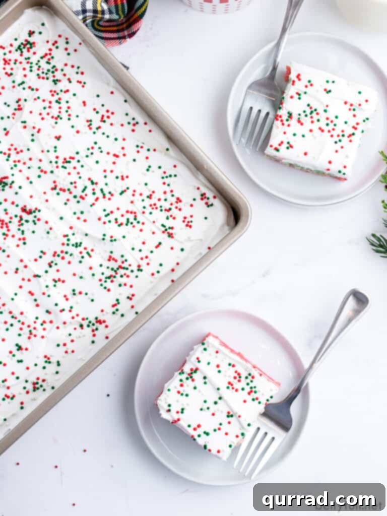 Jiggly Holiday Poke Cake 3 Overhead view of two square pieces of Christmas Jello Poke Cake on plates, adorned with festive sprinkles and accompanied by a fork.