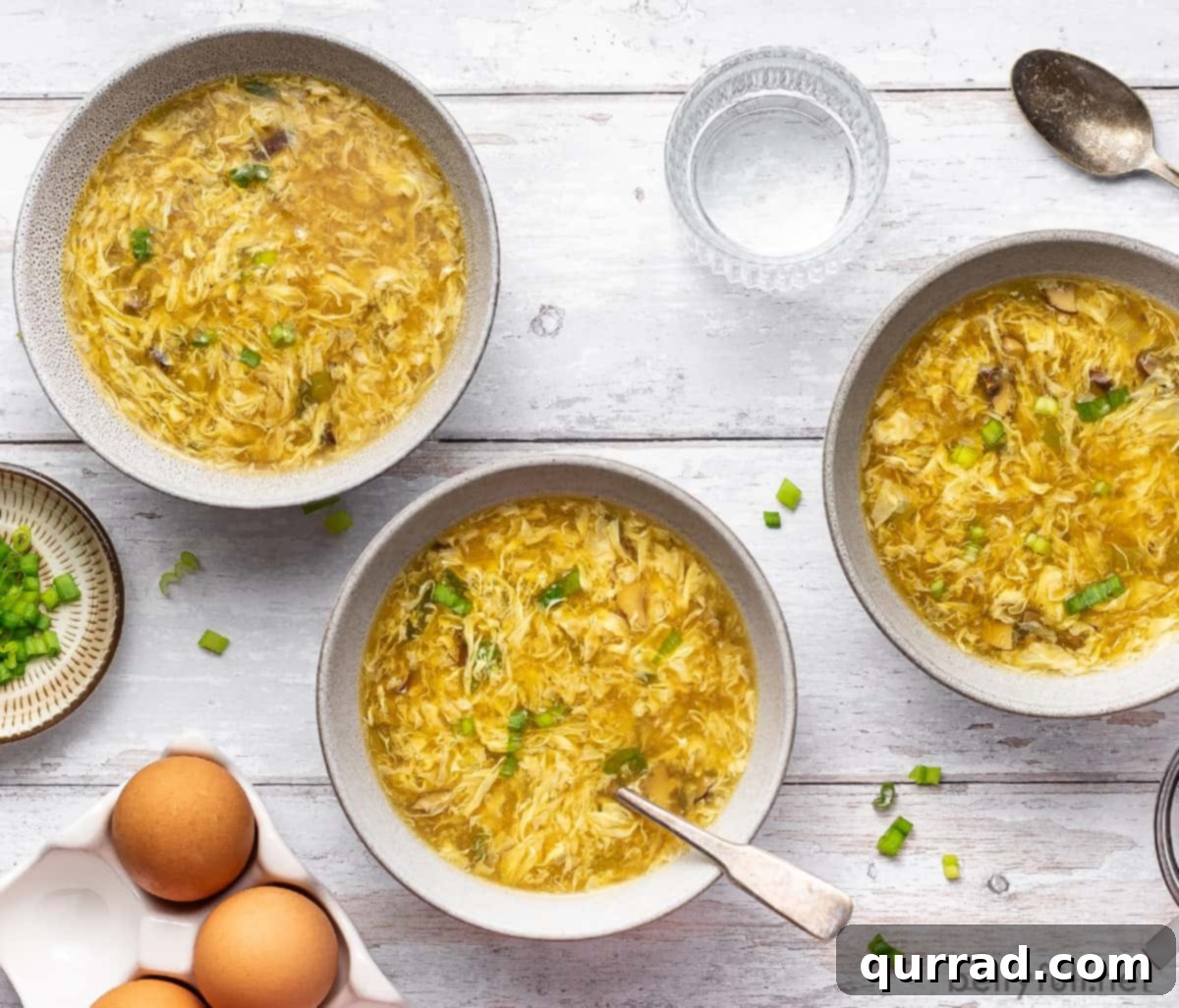 Classic Egg Drop Soup 5 Overhead view of three bowls of easy homemade egg drop soup, garnished with green onions.