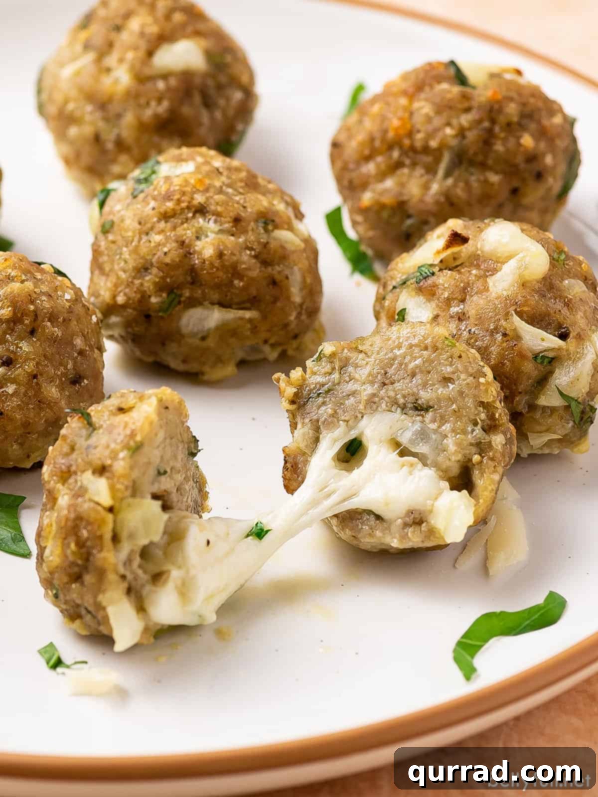 Savory Turkey Meatballs 2 Turkey meatballs on a plate, one cut in half so you can see the cheese inside