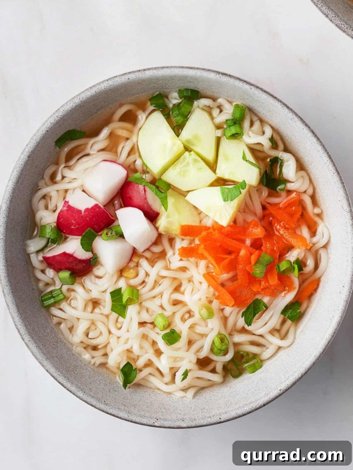 Overhead shot of a steaming bowl of Hot and Sour Ramen Soup, garnished with fresh herbs and vegetables.
