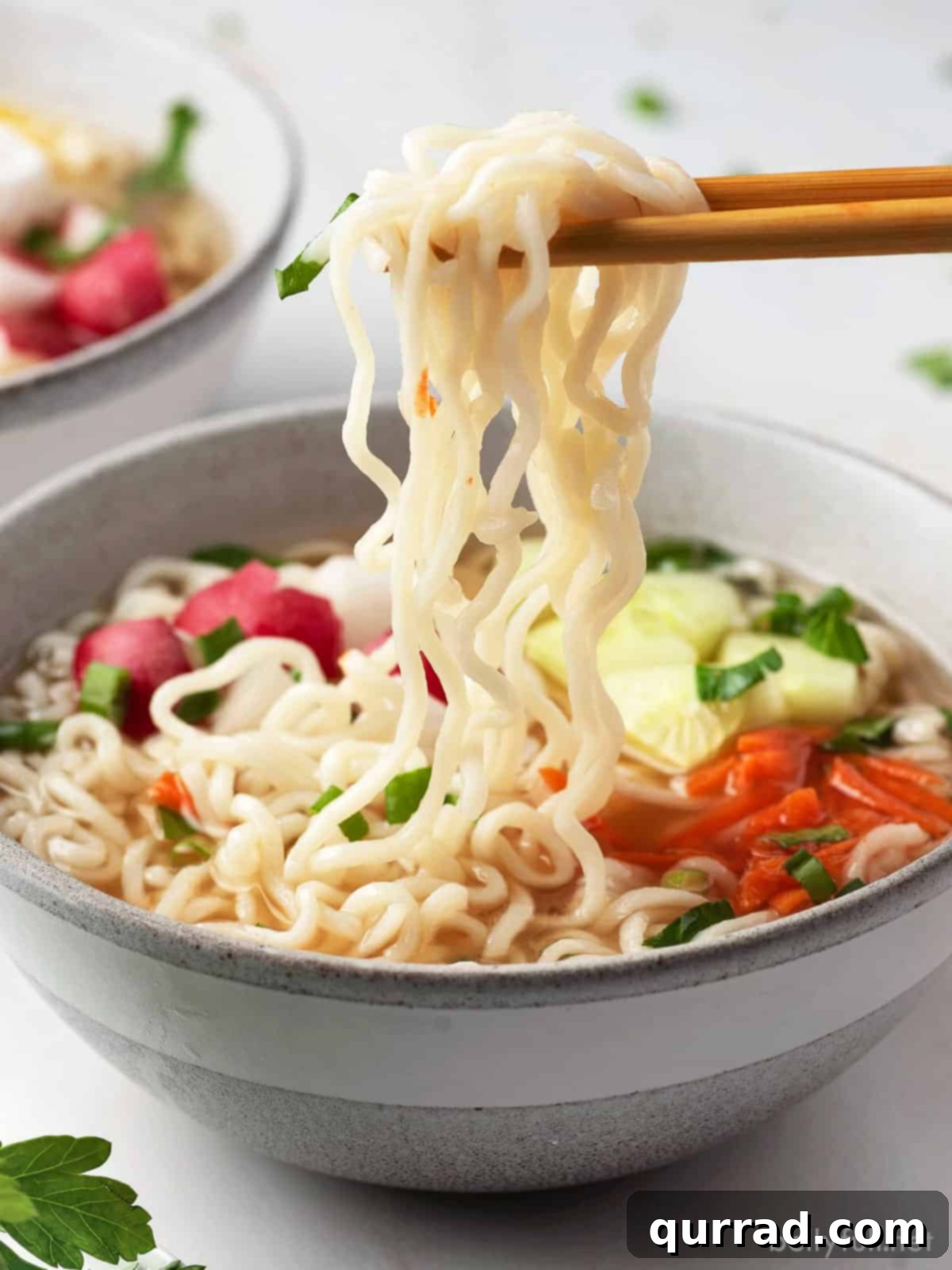 Chopsticks lifting vibrant ramen noodles from a bowl of spicy and sour broth, highlighting the fresh garnishes.