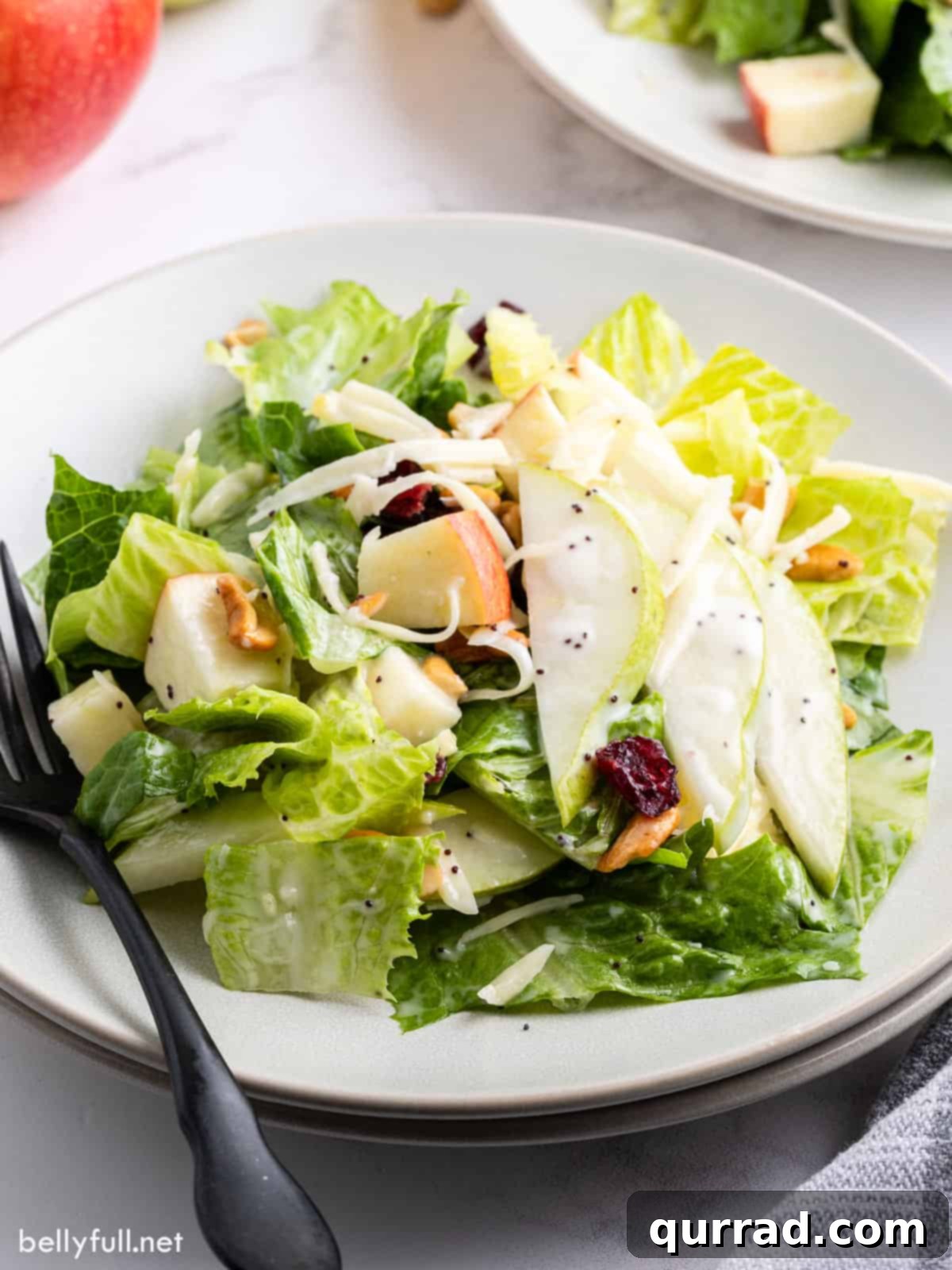 Close-up of pear salad on a white plate, showcasing the vibrant ingredients and creamy dressing.