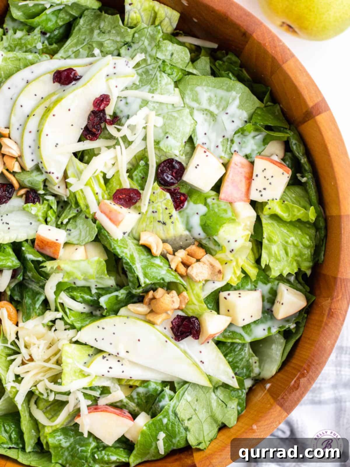 Overhead view of a beautifully arranged pear salad in a rustic wooden bowl, ready to be served.