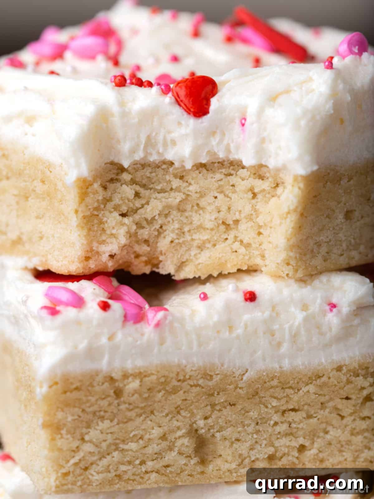 Soft Frosted Sugar Cookie Bars 6 A close-up view of the side of a Frosted Sugar Cookie Bar, revealing its soft texture and a thick layer of creamy frosting. A small bite is missing, hinting at its deliciousness.