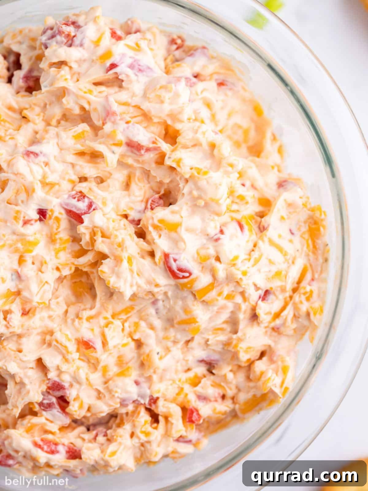 Creamy pimento cheese dip freshly mixed in a large bowl, showcasing its readiness for chilling or serving, with visible pieces of red pimento.