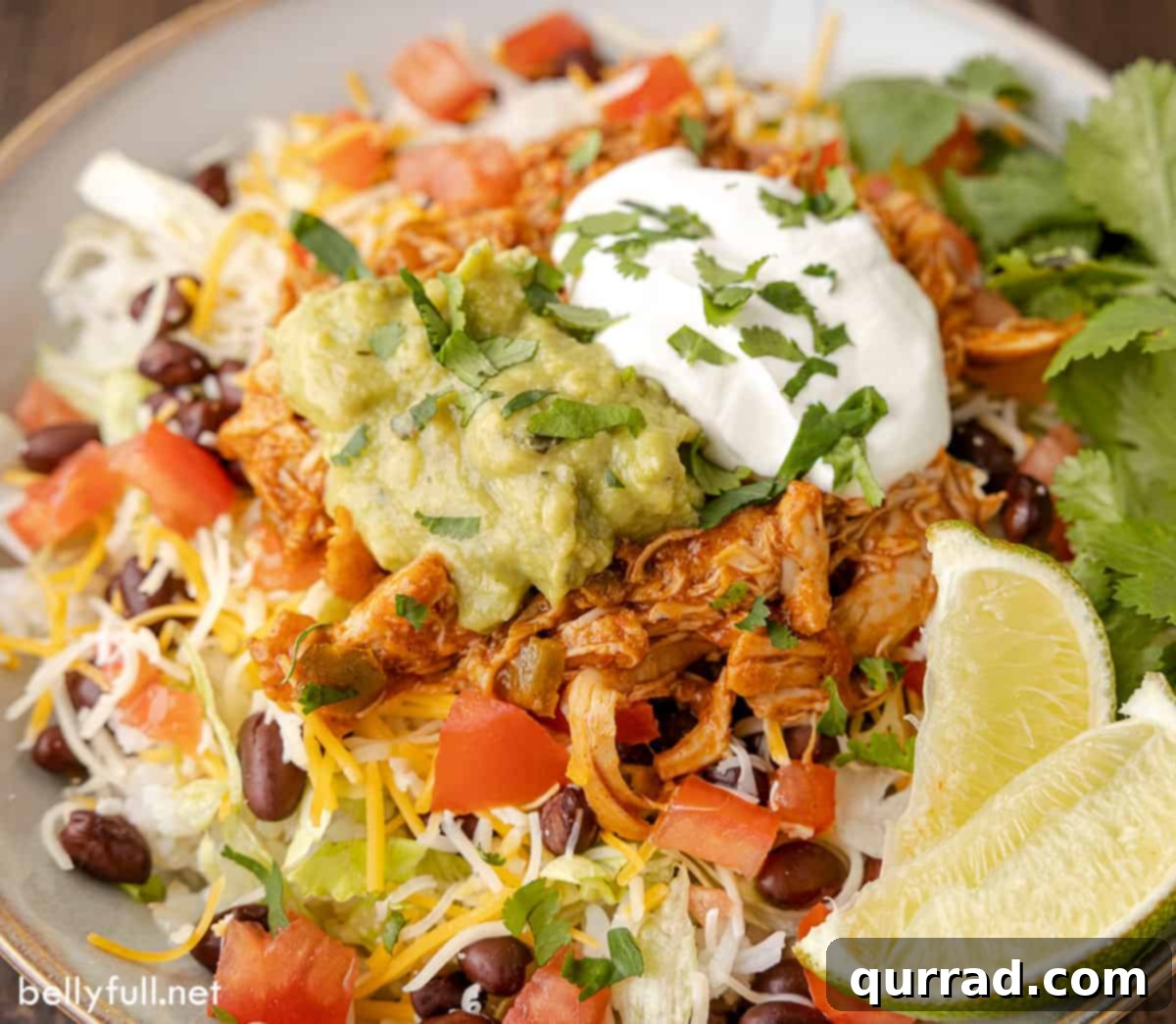 Slow Cooker Cheesy Fiesta Chicken 5 Close-up of queso chicken on a taco salad topped with guacamole and sour cream