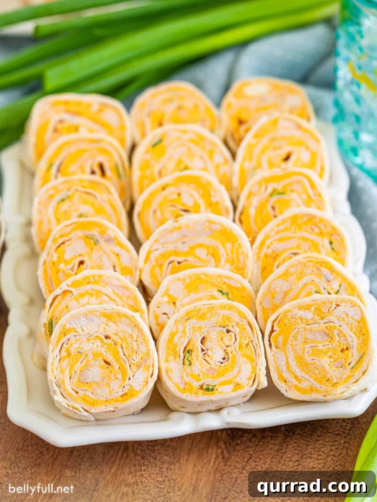 Angled view of buffalo chicken pinwheels on a white serving tray