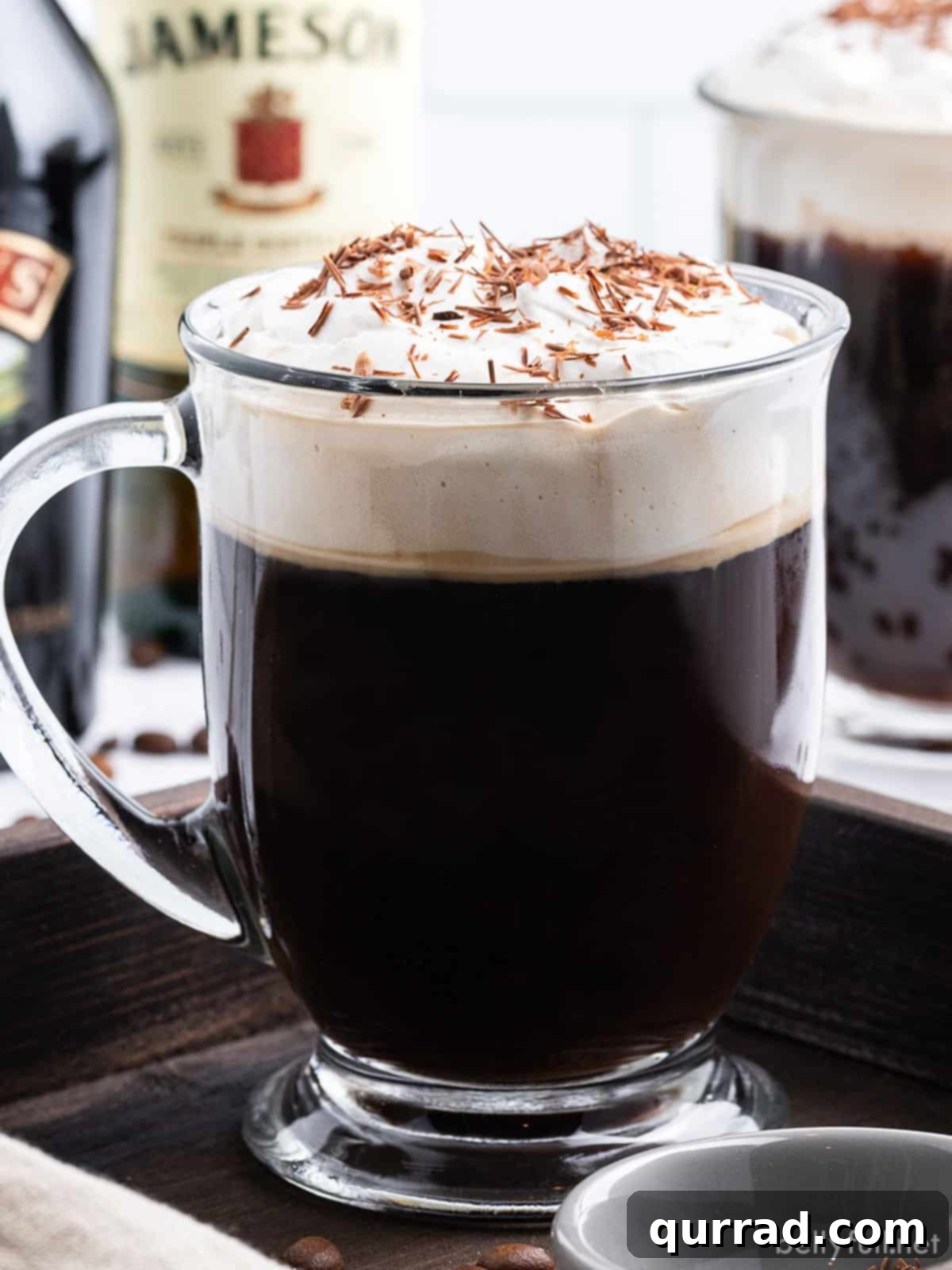 Warm Irish Embrace 2 A tall, elegant glass mug filled with creamy Irish Coffee, garnished with delicate chocolate shavings, inviting warmth and indulgence.