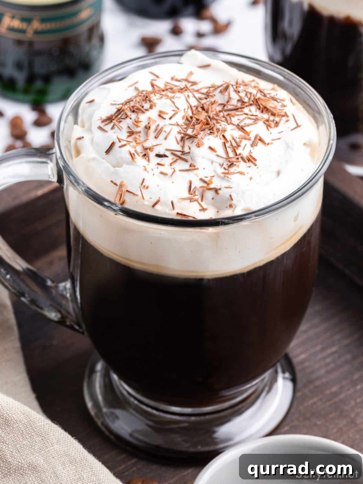 Warm Irish Embrace 3 A beautifully presented glass of Irish coffee, generously topped with fluffy whipped cream and a sprinkle of chocolate shavings, promising warmth and indulgence.