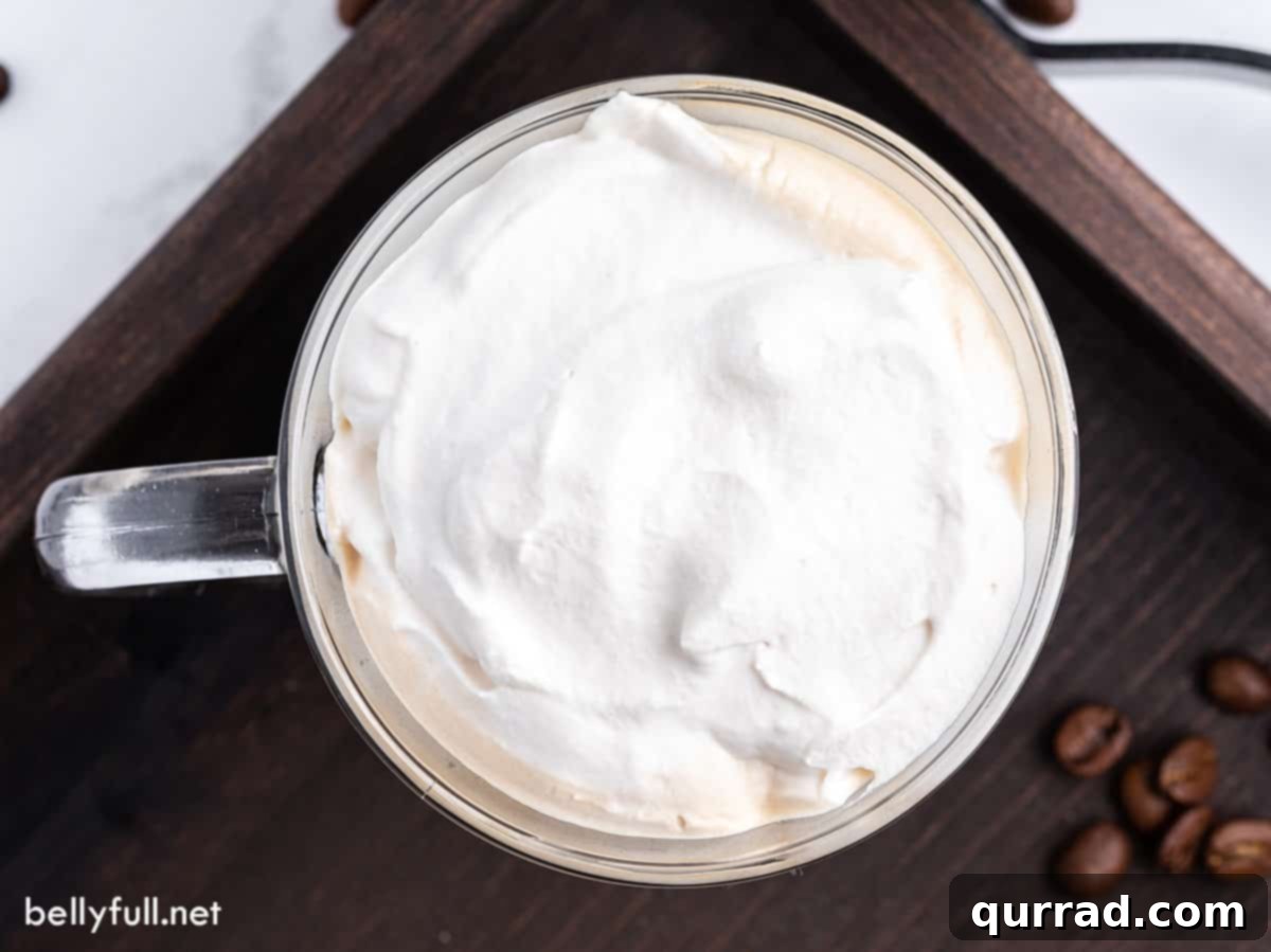 Warm Irish Embrace 4 An inviting overhead view of a glass mug of Irish coffee, showcasing the thick, perfectly dolloped layer of whipped cream on top, ready to be enjoyed.