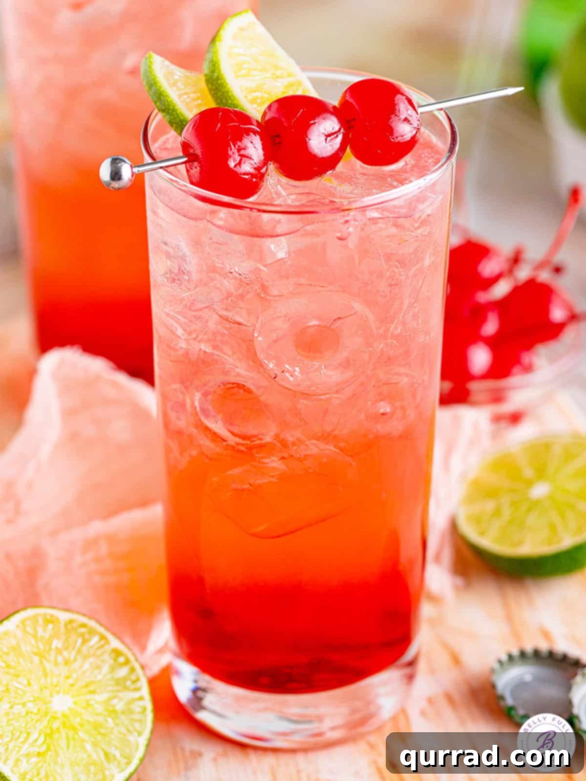 Tipsy Temple 2 Dirty Shirley cocktail in a tall glass with 3 Maraschino cherries, a vibrant pink drink perfect for summer