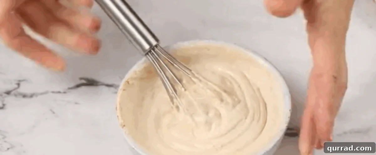 Ultimate Seven-Layer Dip 9 The sour cream layer being mixed in a bowl with a whisk.