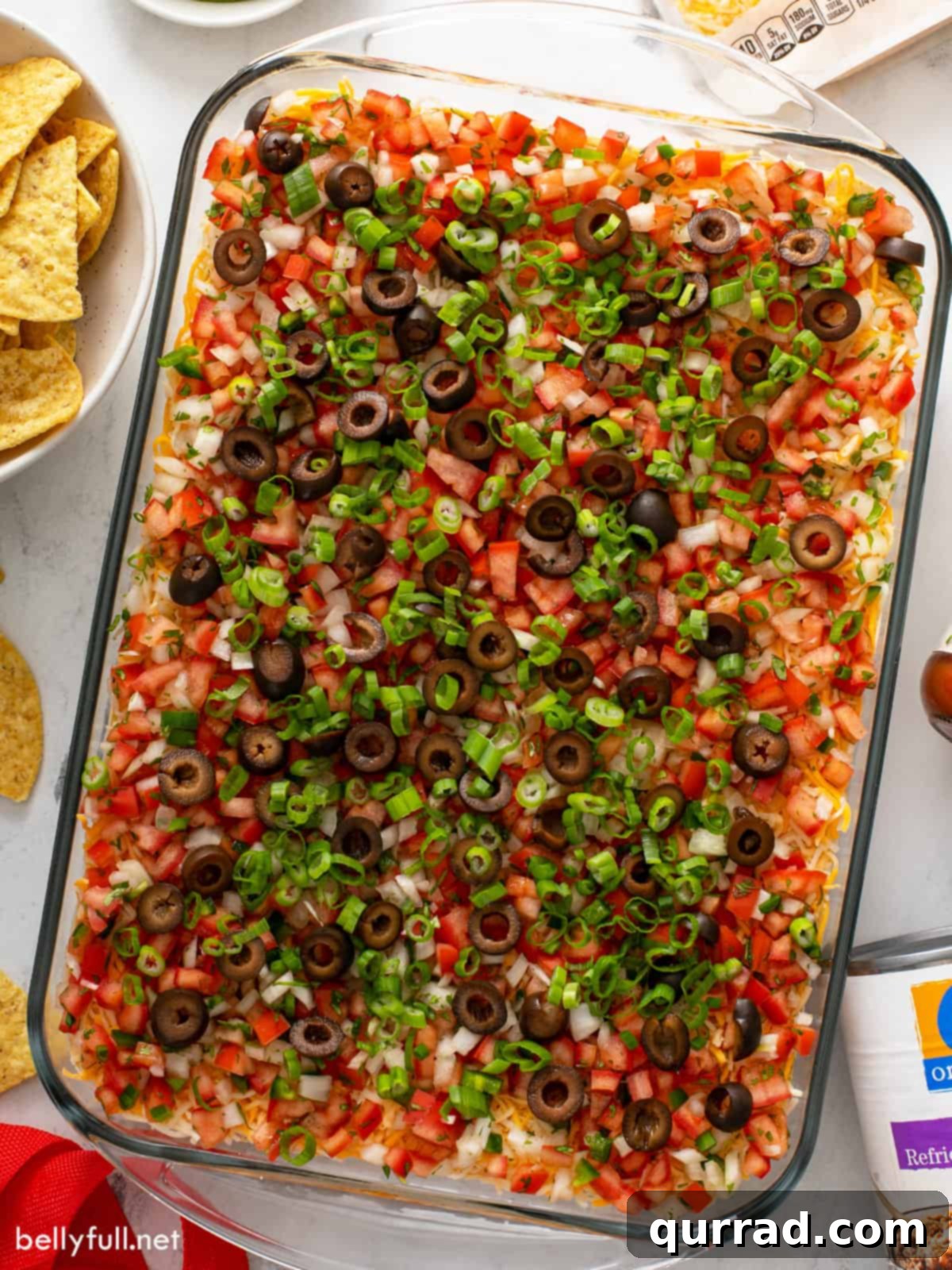Ultimate Seven-Layer Dip 14 Overhead view of a casserole dish filled with a vibrant 7 layer dip, ready to be enjoyed.