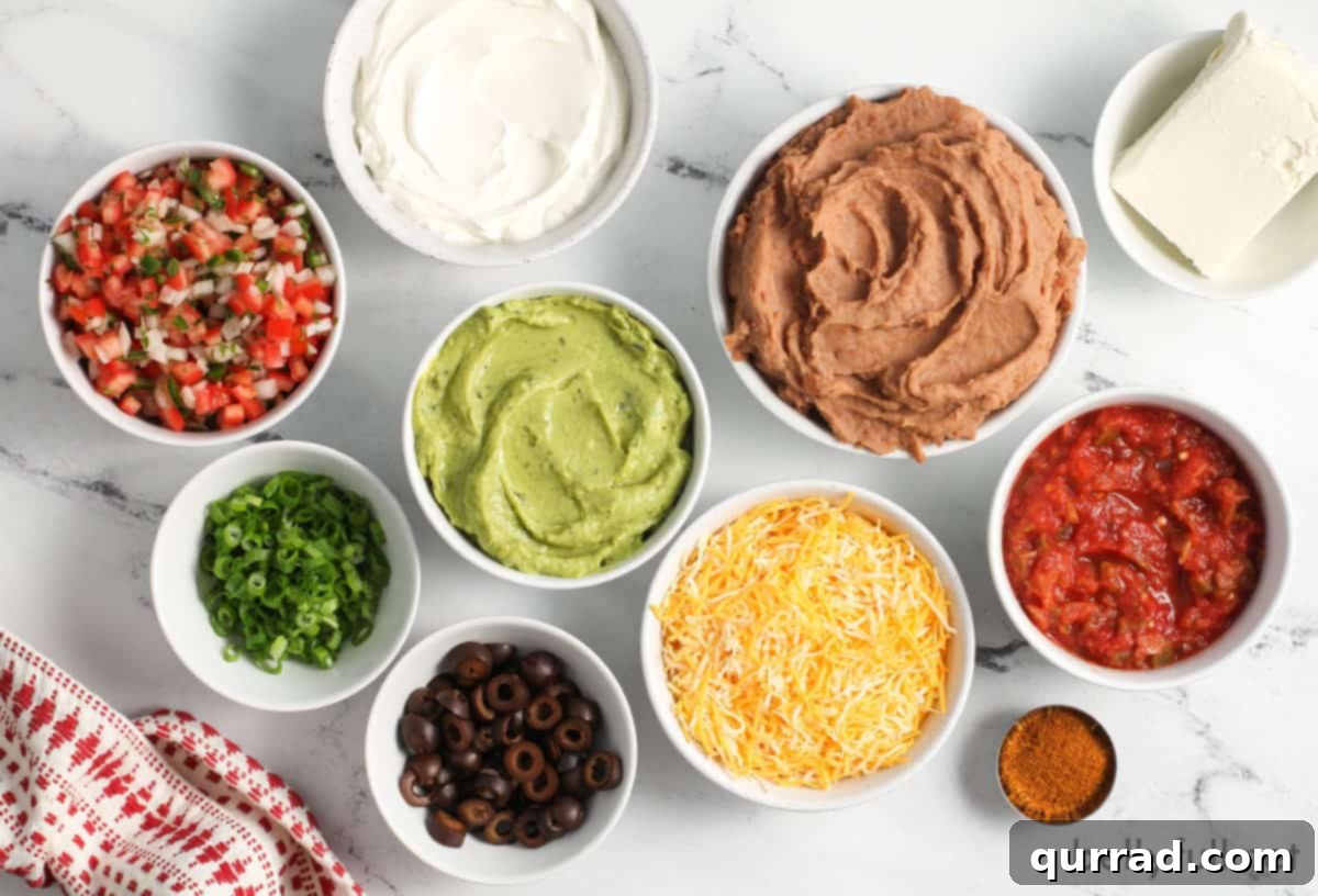 Ultimate Seven-Layer Dip 5 Assorted ingredients for 7 layer dip laid out on a kitchen counter