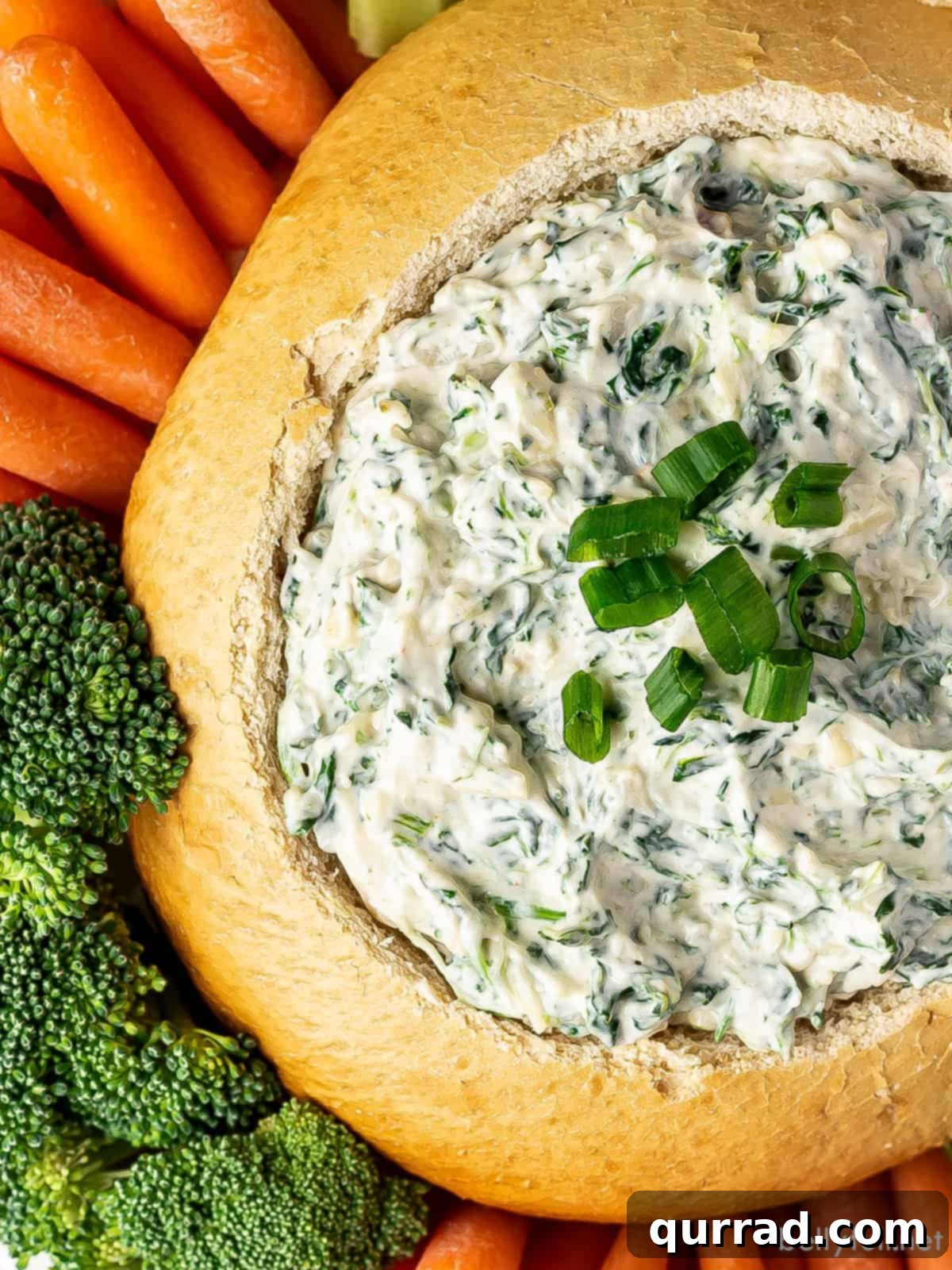 Creamy Spinach Dream 3 Overhead close-up on a bread bowl filled with creamy spinach dip, showcasing the rich texture and flecks of spinach. The edges of the rustic bread bowl are visible, suggesting a delicious and inviting presentation for this classic cold appetizer.