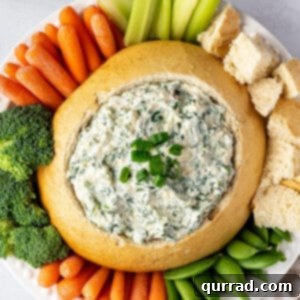 Creamy Spinach Dream 6 Overhead view of spinach dip in a bread bowl surrounded by veggies