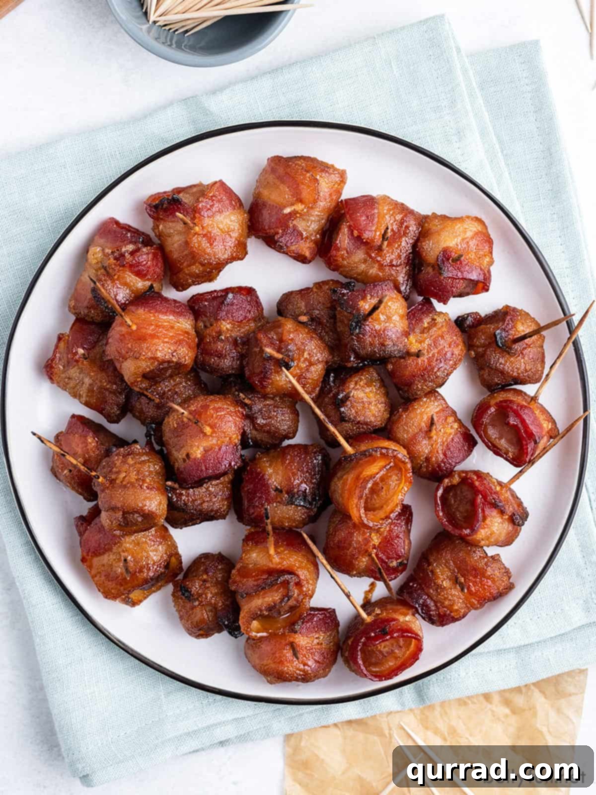 Overhead view of bacon wrapped water chestnuts on a white plate, perfectly golden and inviting