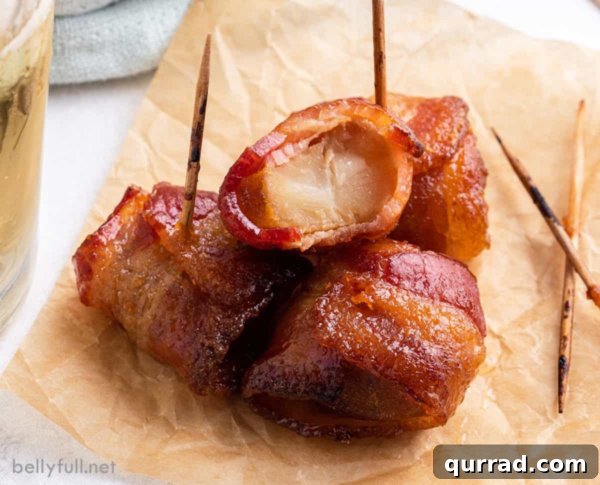 Close-up of 3 water chestnuts wrapped in bacon, with a golden, sticky glaze