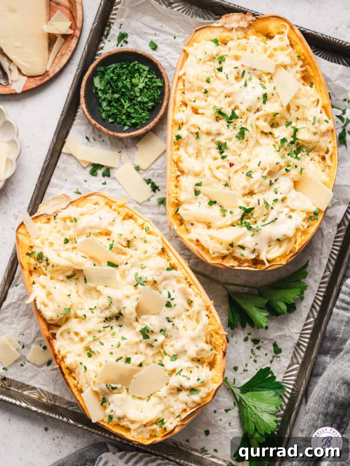 Creamy Spaghetti Squash Alfredo 2 Two halves of spaghetti squash alfredo on a baking sheet, garnished with fresh parsley.