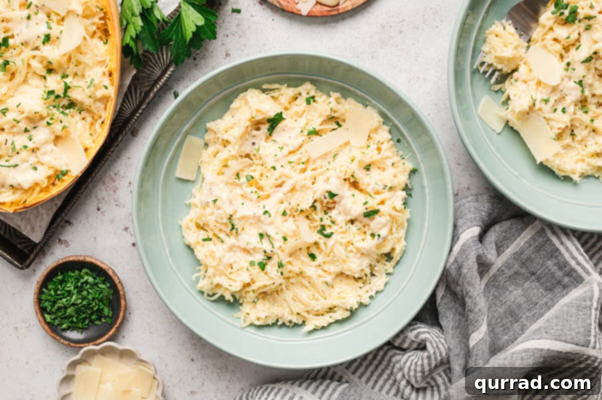 Creamy Spaghetti Squash Alfredo 3 Spaghetti squash alfredo served on a plate with shaved Parmesan cheese and a sprinkle of black pepper.