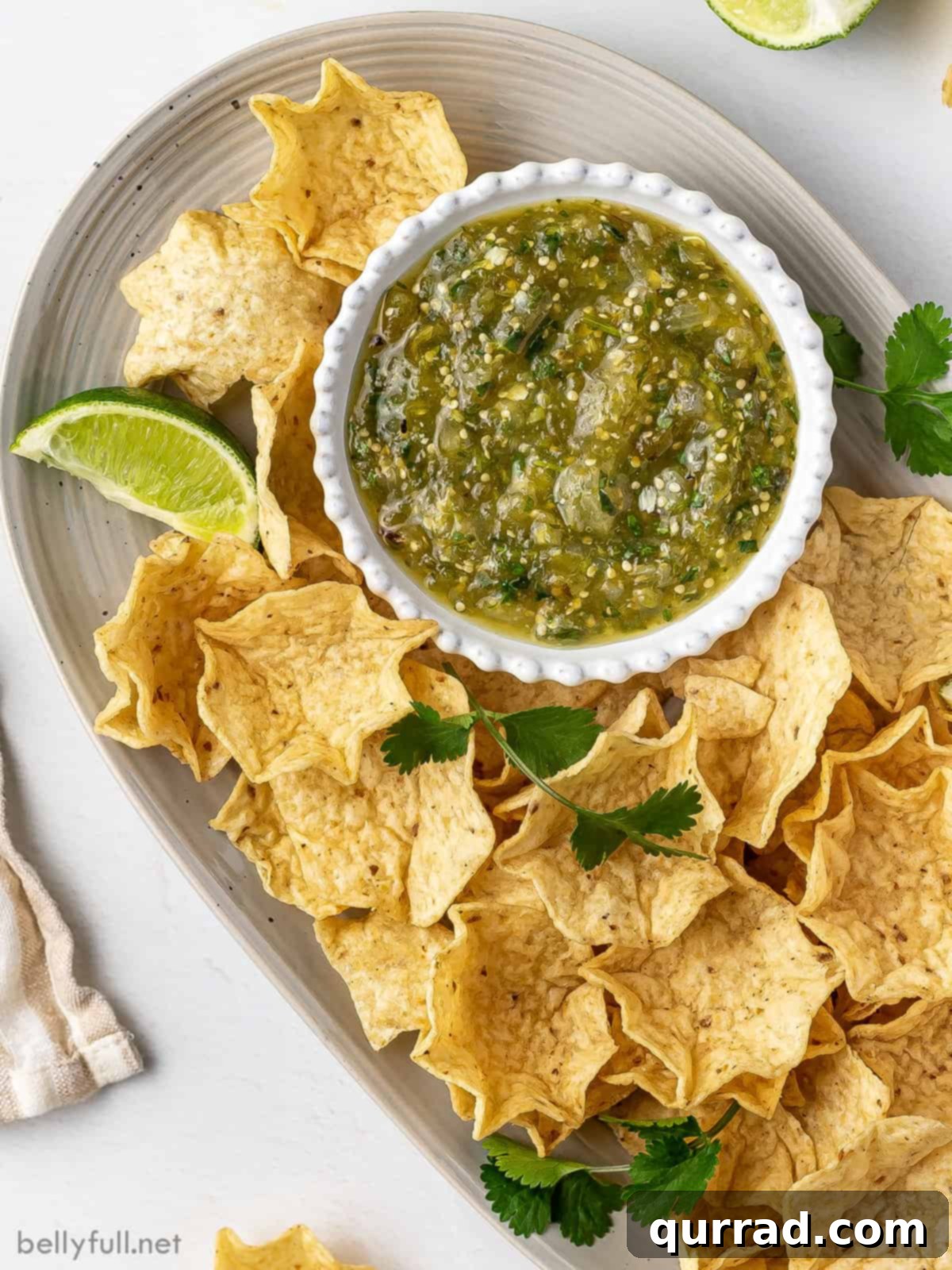 Overhead view of a platter with tortilla chips and a small bowl of salsa verde