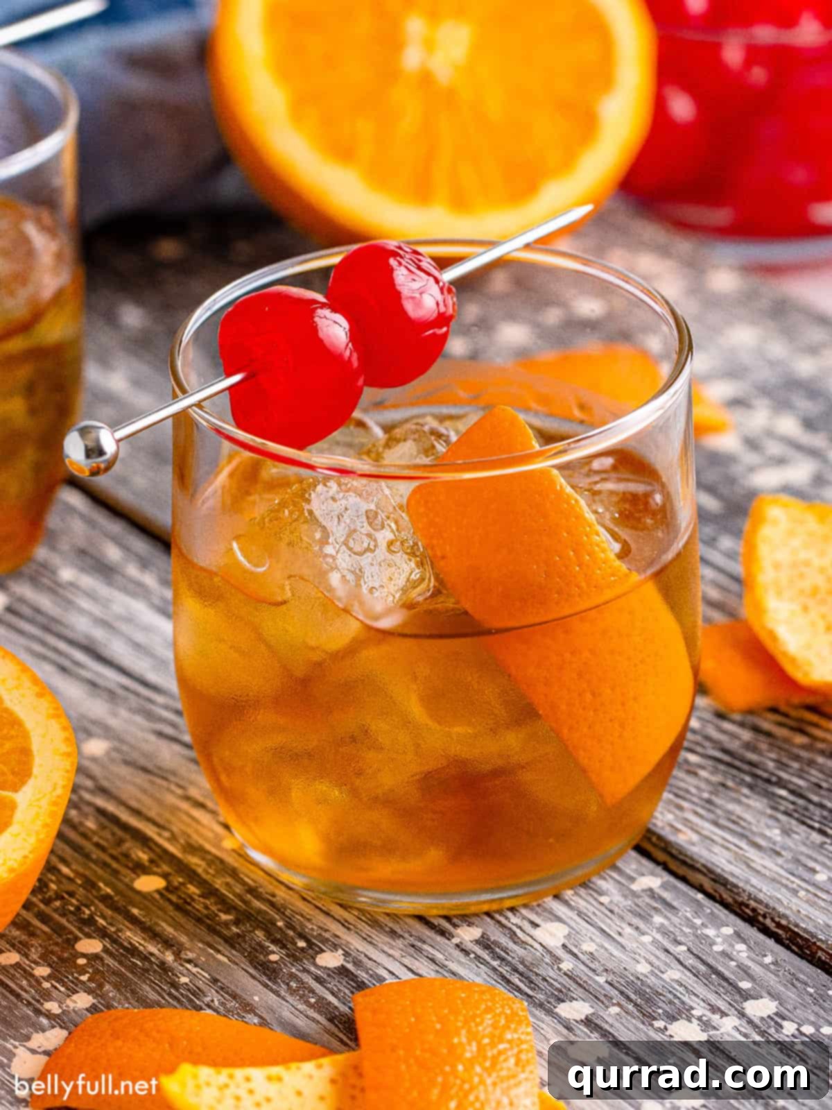 Timeless Elegance 2 Angled view of an old fashioned cocktail in a classic lowball glass, garnished with an orange peel and a cherry.