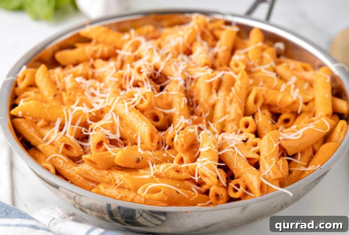 Penne alla vodka in a skillet topped with parmesan cheese