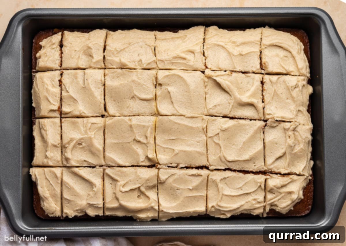 Velvet Tomato Spice Cake 3 A freshly baked and frosted Tomato Soup Cake, cut into perfect squares, rests invitingly in a baking pan. Each square promises a moist, spiced treat, ready to be enjoyed.