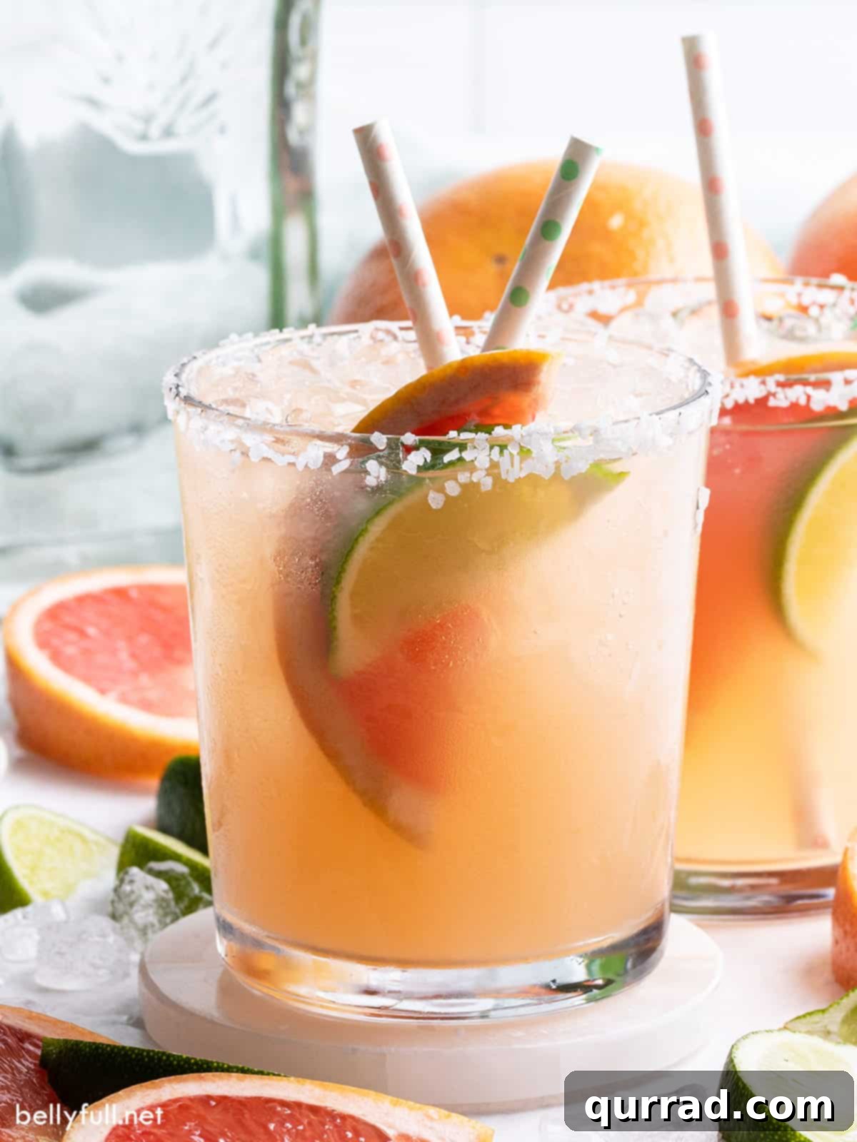 Close-up side view of a Paloma cocktail in a salt-rimmed glass, garnished with a lime wedge.