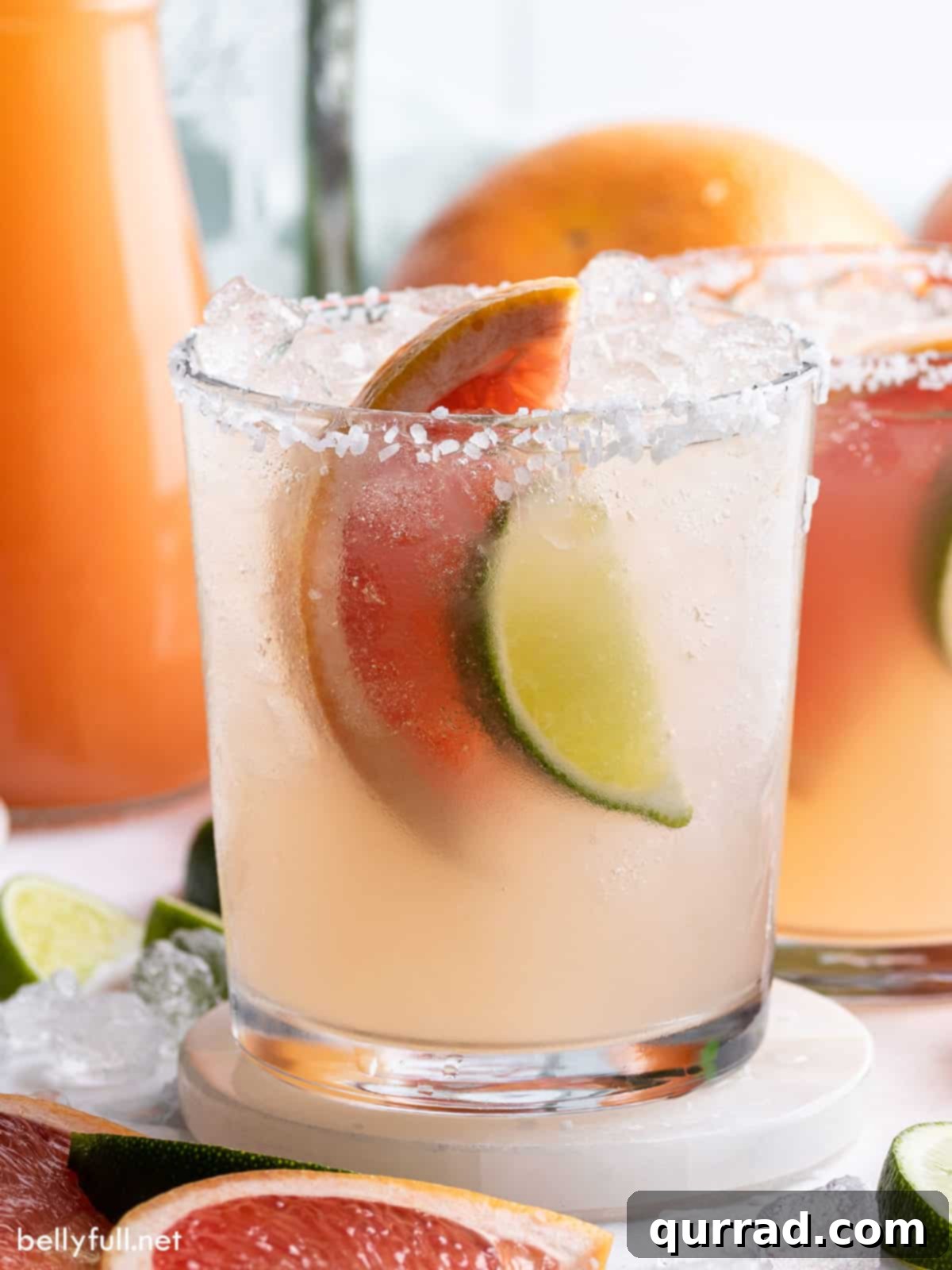 A vibrant Paloma cocktail in a tall glass, garnished with a grapefruit wheel and lime wedge.
