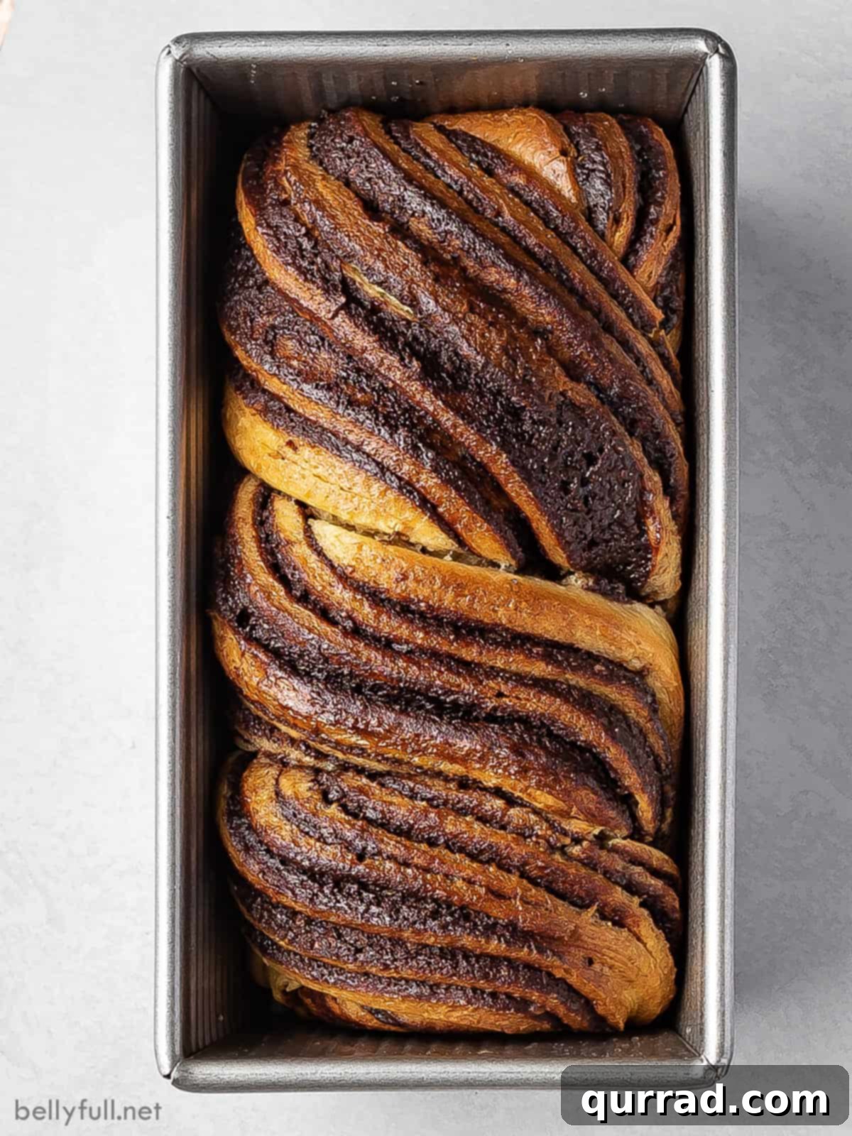 Decadent Chocolate Babka 3 Overhead view of a beautiful chocolate babka bread, freshly baked and nestled perfectly in a loaf pan, ready to be sliced.