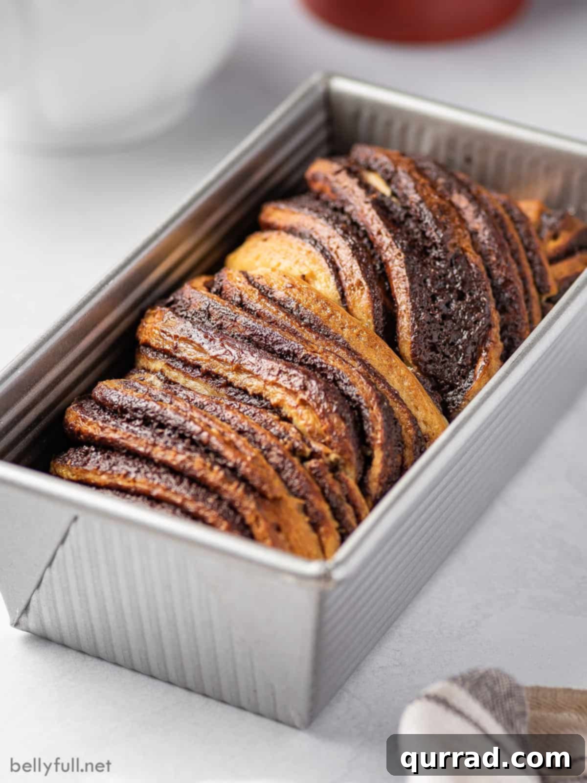 Decadent Chocolate Babka 6 An inviting angled view of a baked chocolate babka loaf in a pan, glistening with syrup.