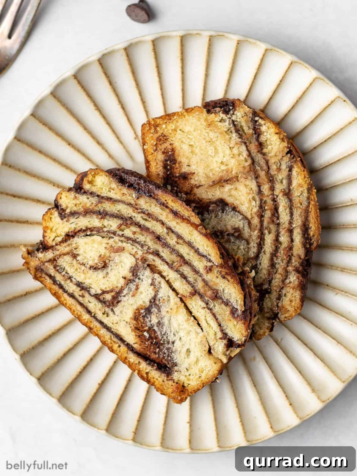 Decadent Chocolate Babka 7 Overhead view of two perfectly sliced pieces of chocolate babka, showing the intricate layers and inviting chocolate filling.