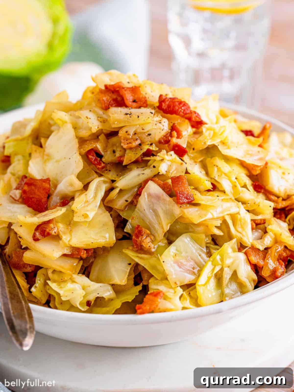 Golden Skillet Cabbage 2 Angled view of a bowl of fried cabbage with crispy bacon bits