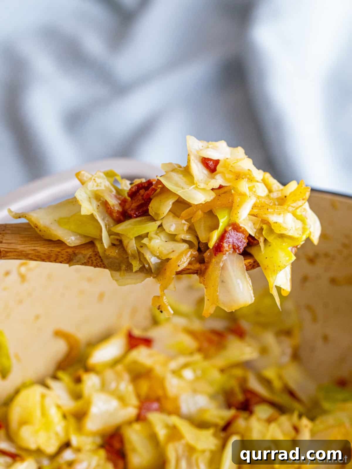 Golden Skillet Cabbage 3 A wooden spoon serving fried cabbage with bacon