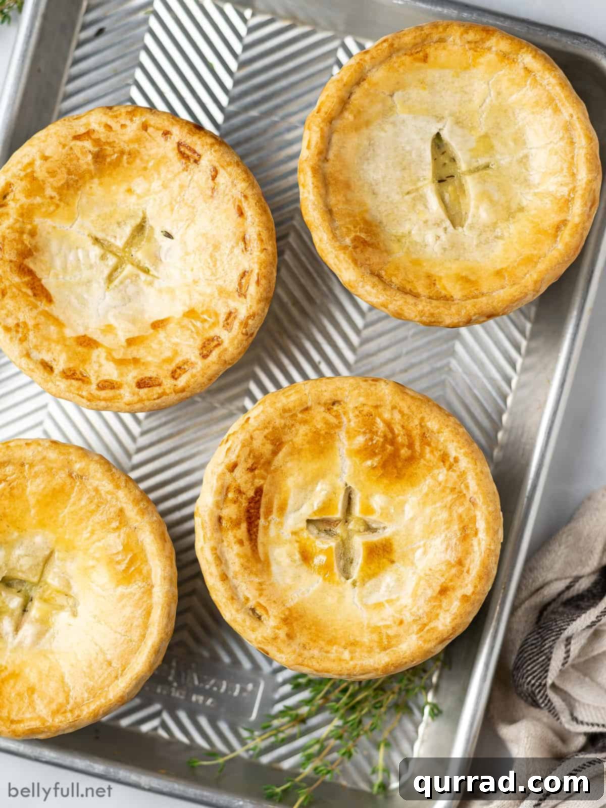 Overhead view of 4 golden-brown chicken pot pies arranged on a baking sheet