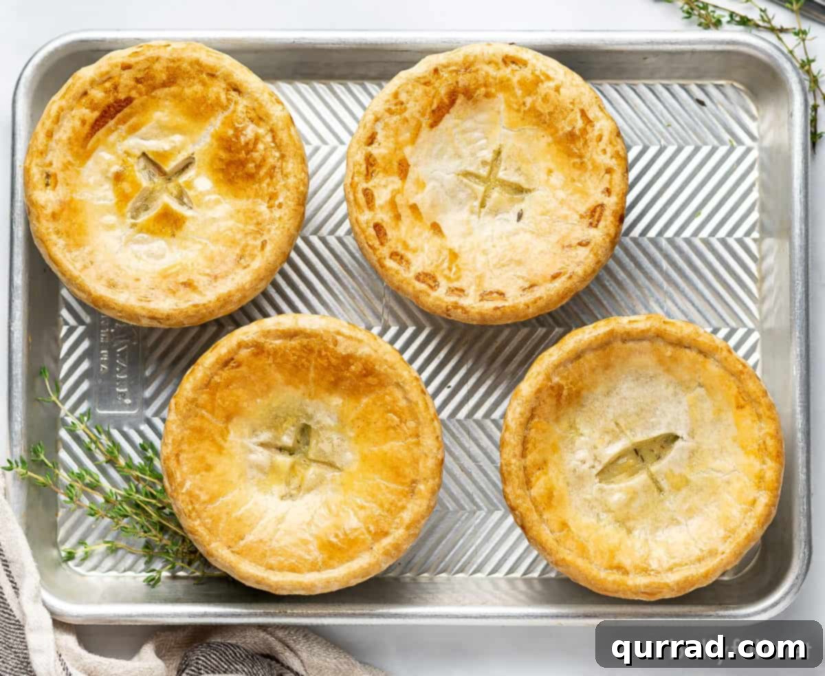 Overhead view of 4 mini chicken pot pies arranged neatly on a baking sheet, freshly baked